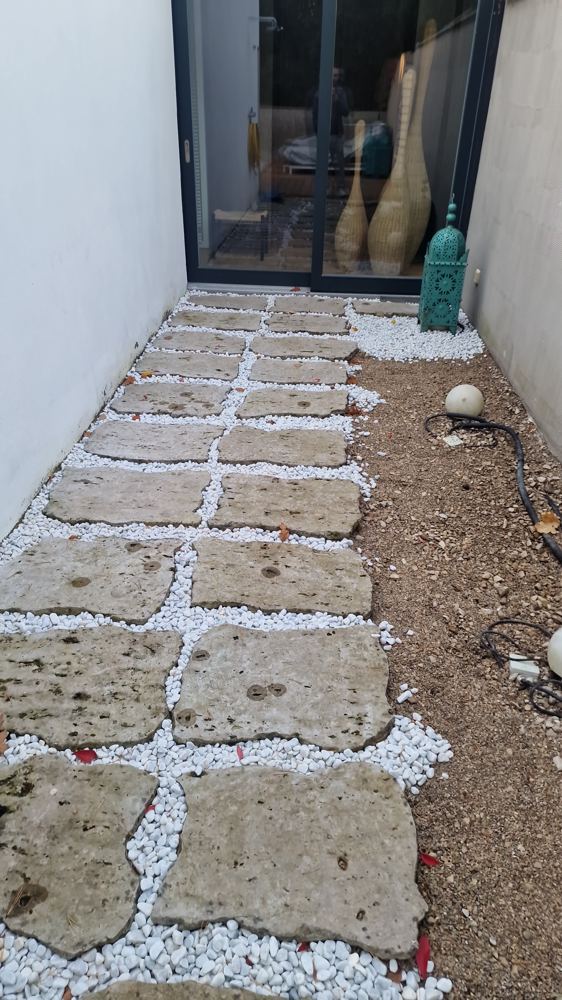 Gepflegte Außenanlage mit Trittplatten und weißem Kies